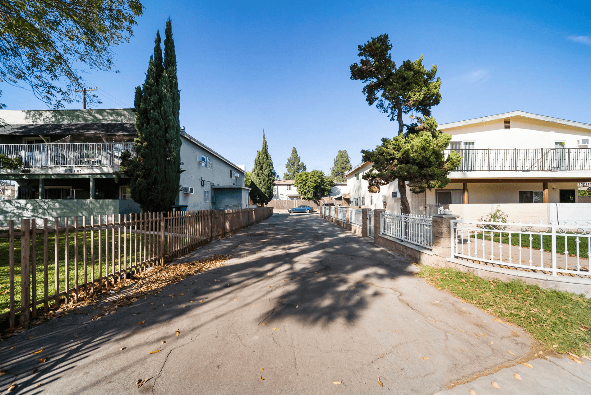 A residential street with houses on both sides and trees lining the street.